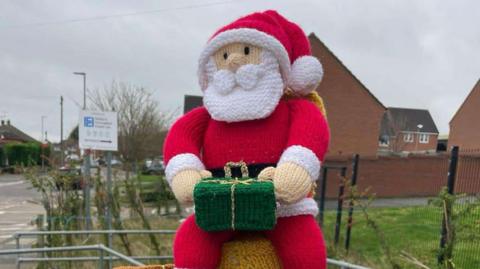 A small knitted Santa Claus as part of a post box topper