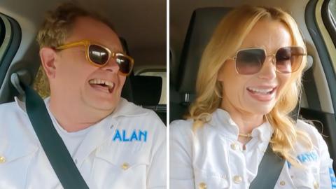 Composite image of Alan Carr and Amanda Holden laughing in a car, both wearing sunglasses and white overalls
