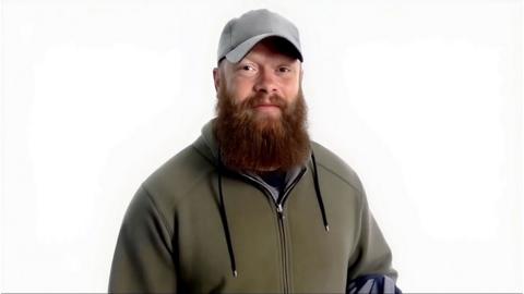 Man in green jacket with baseball hat