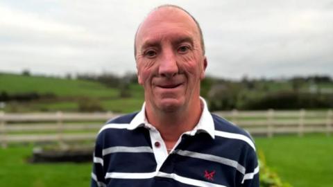 Tom Hadden standing in a field wearing a stripey top