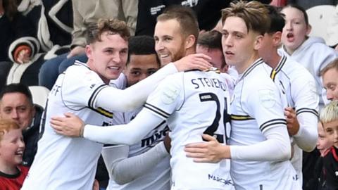 Luke Young of Cheltenham Town celebrates scoring a goal with team-mates