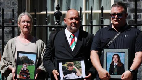 Stuart Stephens is joined by two other parents outside Downing Street holding up images of their deceased children.