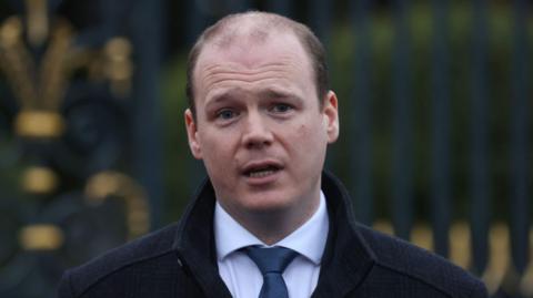 Gordon Lyons wearing white shirt and blue tie