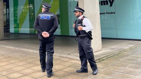 Two police officers standing outside Westminster Academy entrance