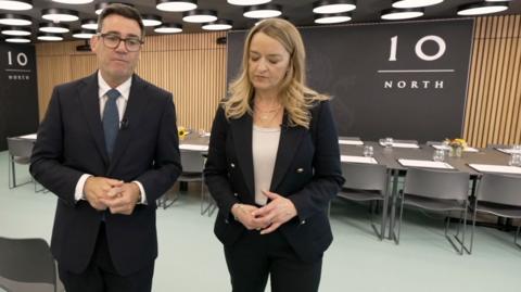Andy Burnham and Laura Kuenssberg walking in an office with '10 North' written on a signbehind them