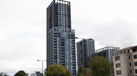 The Fold is seen as a modern glass and steel tower block in Croydon with balconies, photographed from street level.