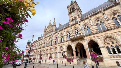 A large gothic building in the centre of a town.