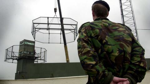 A uniformed soldier overlooks thee dismantling of Army observation towers in South Armagh.