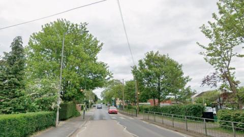 A Google street view image of Welton Road, Brough. The road is lined by green trees and bushes. A pedestrian crossing is visible as well as a petrol station in the distance.