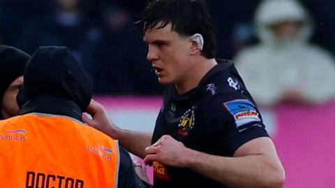 Tom Hooper is helped off the field by club medical staff