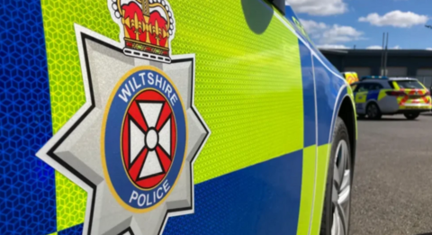 The side of a parkd car which says Wiltshire Police on the side, over a blue and yellow livery