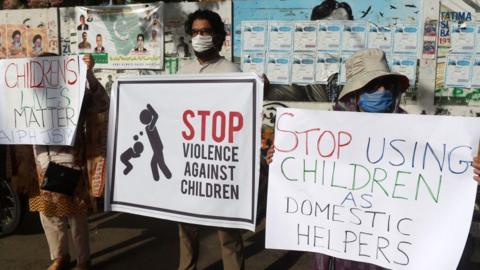 Activists of Civil Society carry placards during a protest against child labour and violence against children, in Karachi on June 8, 2020