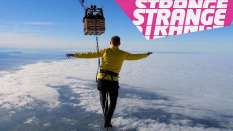 A man walking a rope towards a hot air balloon