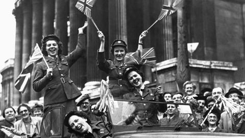 Women from the WRAC waving British flags from a car at the VE Day celebrations in Trafalgar Square