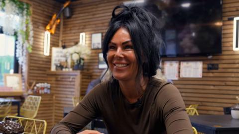 smiling woman sat in a cafe