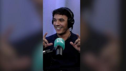 Freddie Fraser smiling in front of a green mic, wearing headphones.