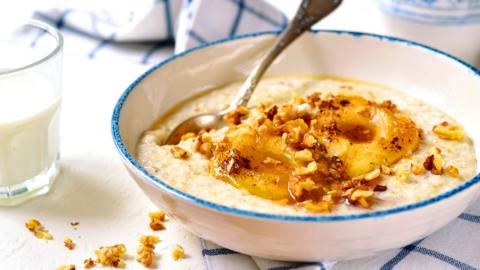A bowl of porridge topped with fruit, nuts and honey