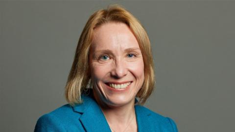 North Shropshire MP Helen Morgan in her official parliamentary potrait. She is smiling and wearing a blue blazer against a grey background. 