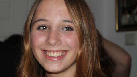 Alice Figueiredo, a young woman with hazel eyes and reddish-brown hair, smiling in a candid photograph.