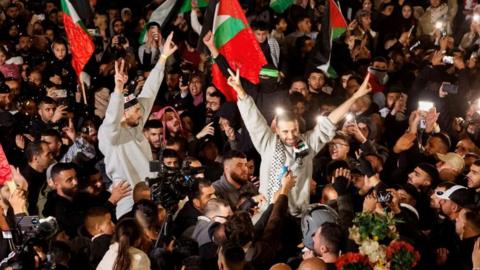 Two men in grey jumpers held up by crowd as they raise their hands