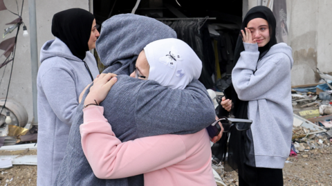 Two women hug as another looks on tearfully outside a damaged home in Lebanon