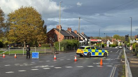 A police car on a main road next to a police cordon