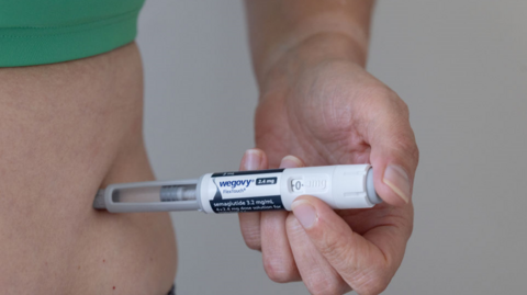 Person injecting Wegovy into their side 