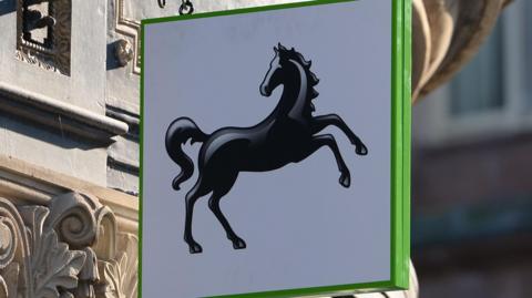 A sign shows the LLoyds Banking Group logo - a black horse on a white square background with a green border.