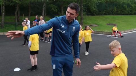 James Anderson runs a youngster through a bowling drill at an event for Chance to Shine