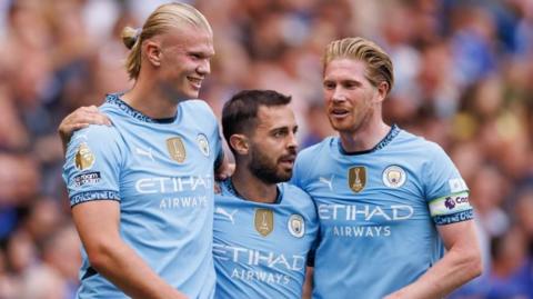 Erling Haaland celebrating a goal with Bernardo Silva and Kevin De Bruyne