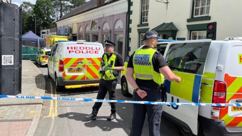 Police officers standing next to a cordoned-off area in Church Street, Welshpool