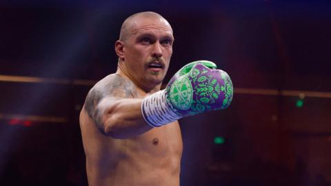 Oleksandr Usyk holds out his purple and green boxing glove