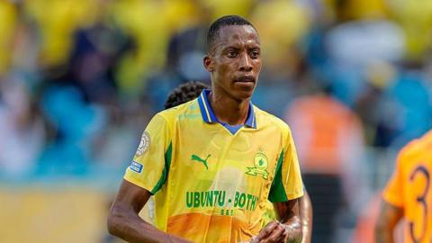 Footballer Divine Lunga is seen during a match in a yellow and green Mamelodi Sundowns shirt