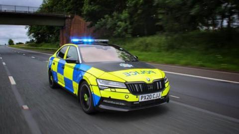 A generic picture of a Cumbria Police car driving along a motorway. The car has its blue lights on. It is driving at speed.