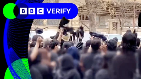 Dozens of protesters waving black cloths and wearing masks