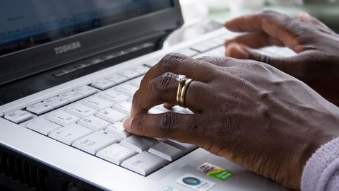 Close-up of a woman's fingers tapping on a laptop keyboard