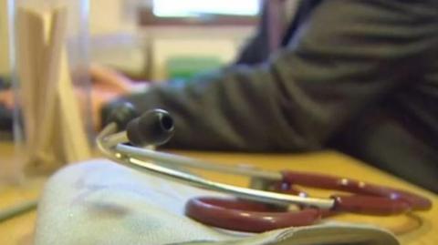 Stethoscope on a desk in front of a doctor