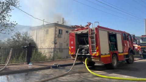 Firefighters put out a blaze at a residential building hit by a Hezbollah rocket in Kiryat Shmona, northern Israel (9 October 2024)