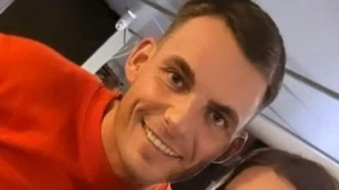 Marc Webley in a red shirt smiling at camera