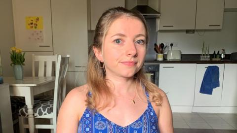 Abbi Brown, a young blonde woman wearing a patterned blue sleeveless top