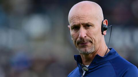 Alan Dickens in a tracksuit and with an earpiece in his left ear ahead of a Newcastle game