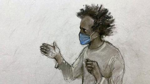 A court sketch of Axel Rudakubana wearing a grey top. He has black hair and is wearing a surgical mask over his nose and mouth.