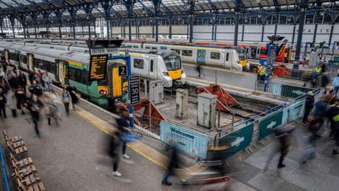 Railways at a station as passengers walk on the platforms