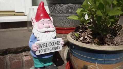Gnome holding a sign saying welcome to the garden.