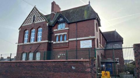 The former building of the school, which staff and students had to leave after it was called structurally unsound during an inspection. It is a three-storey, red brick building with tall windows and decorative detailing.