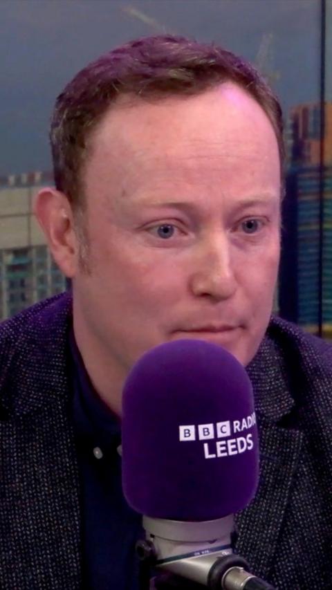 A man in a BBC Radio Leeds studio behind a purple microphone
