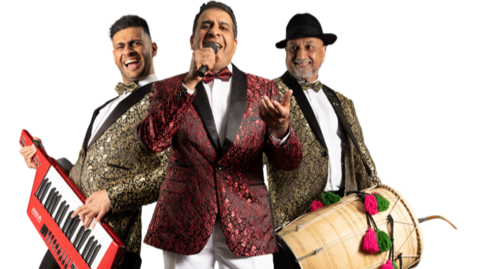 The band are wearing decorative suits, Aamir has a keyboard, Amjad has a microphone and Surinder has a drum. 