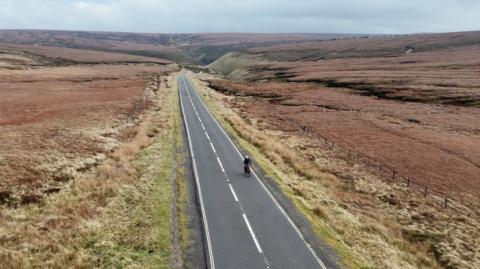 A lone cyclist cycles along the A57 Snake Pass in Derbyshire