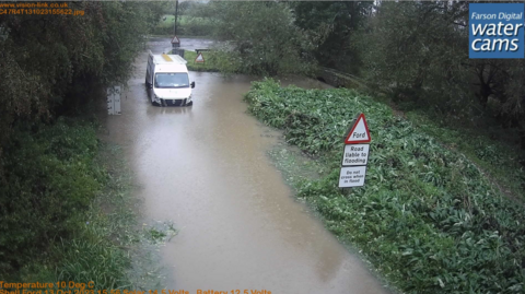 A white van surrounded and stuck in water