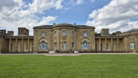 Honey-coloured neoclassical pillars on either side of the front of Heaton Hall. It looks out over a green lawn